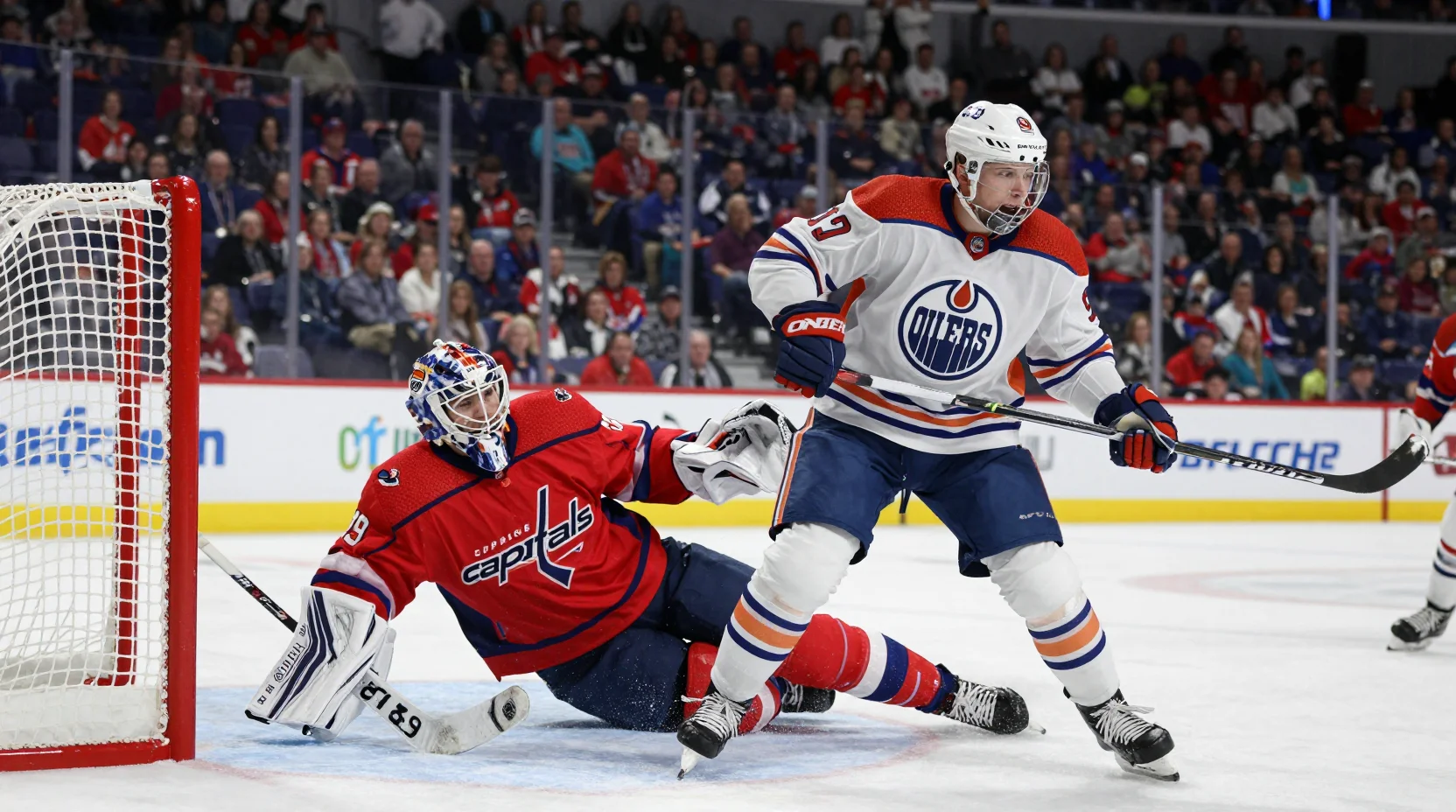NHL game action: Oilers forward winding up for slapshot as Capitals goaltender dives to make save