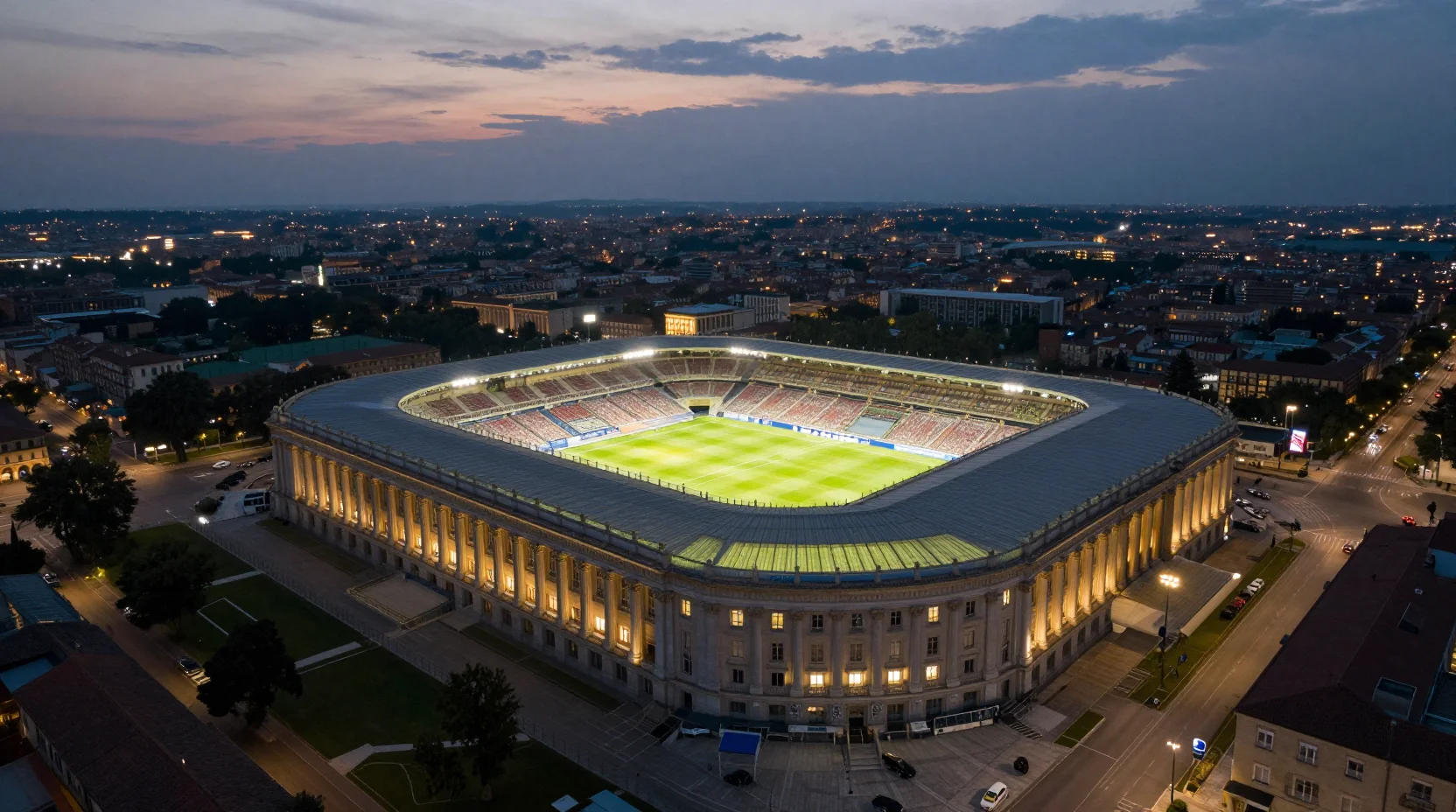 Dramatic aerial view of Stadio Luigi Ferraris at dusk, packed with passionate fans creating a sea of red and blue colors under floodlights