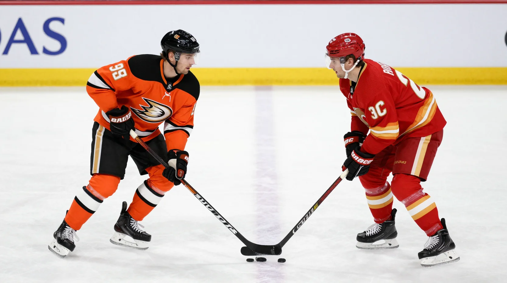 Two NHL hockey teams facing off on a professional ice rink - Anaheim Ducks and Calgary Flames at center ice face-off